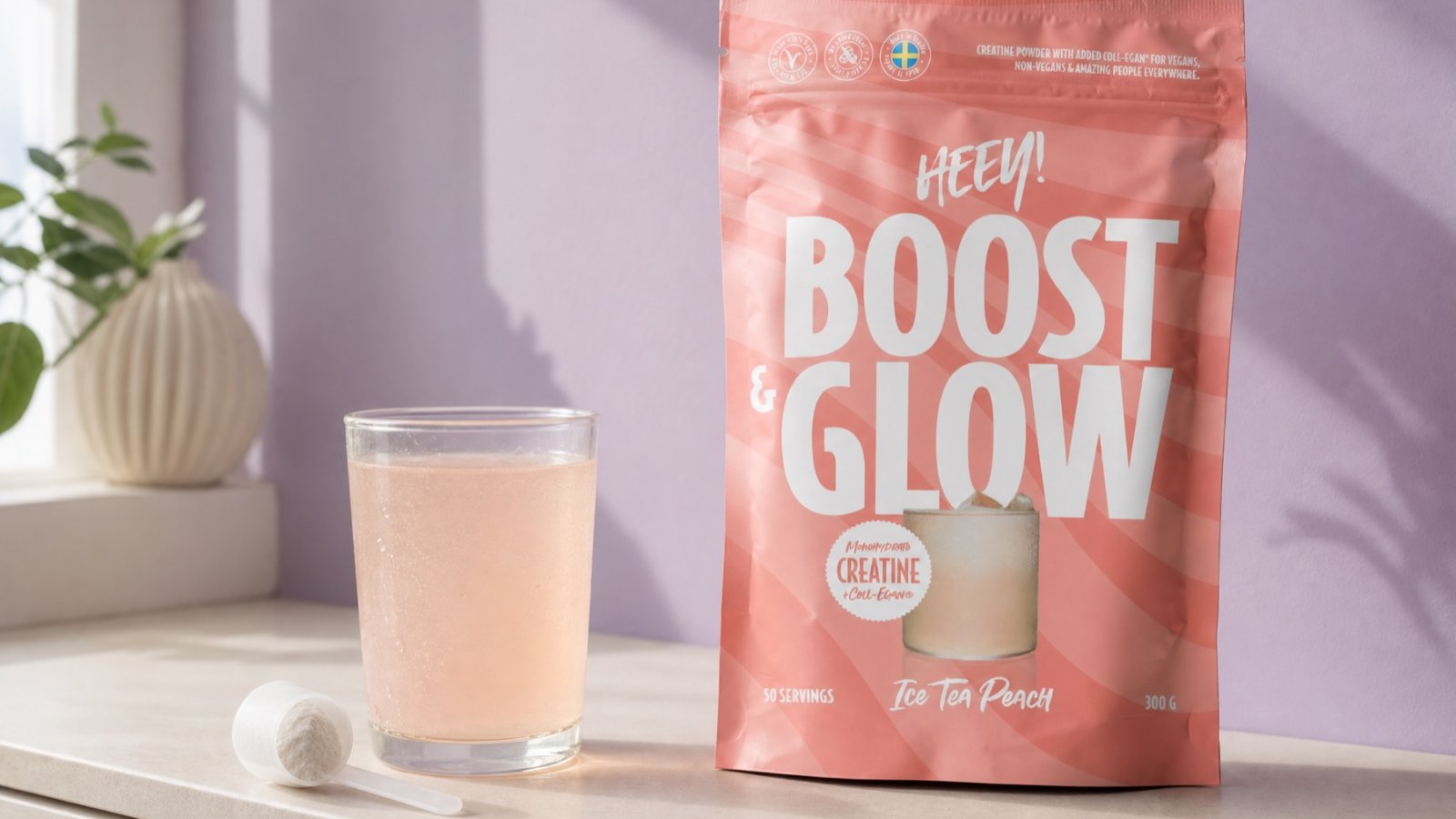 Heey! Boost & Glow Ice Tea Peach med Coll-egan® vegansk kollagenbyggare, glas och skopa i fönsterljus