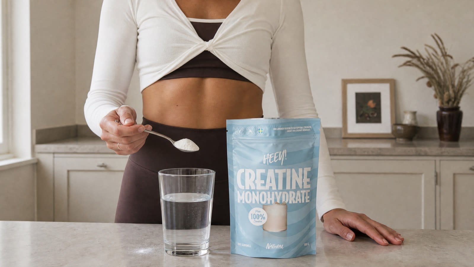Skopa med veganskt kreatinpulver från Heey! bredvid ett glas vatten, 3 gram kreatin per dag