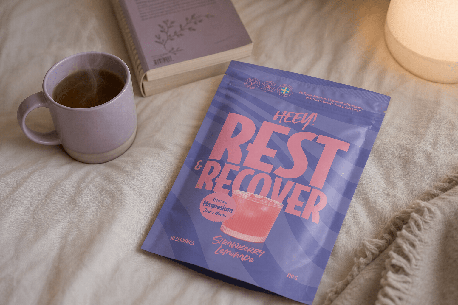 Vegansk magnesium för sömn, Heey! Rest & Recover bredvid en kopp te på sängen, kvällsrutin med magnesium glycinat