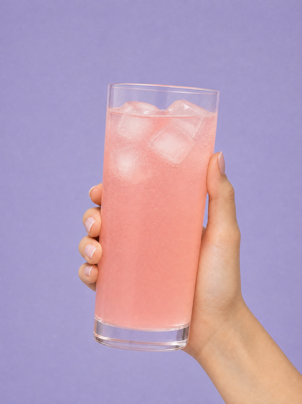 Hydrate & Glow how-to step 3: hand holding a glass of pink electrolyte drink